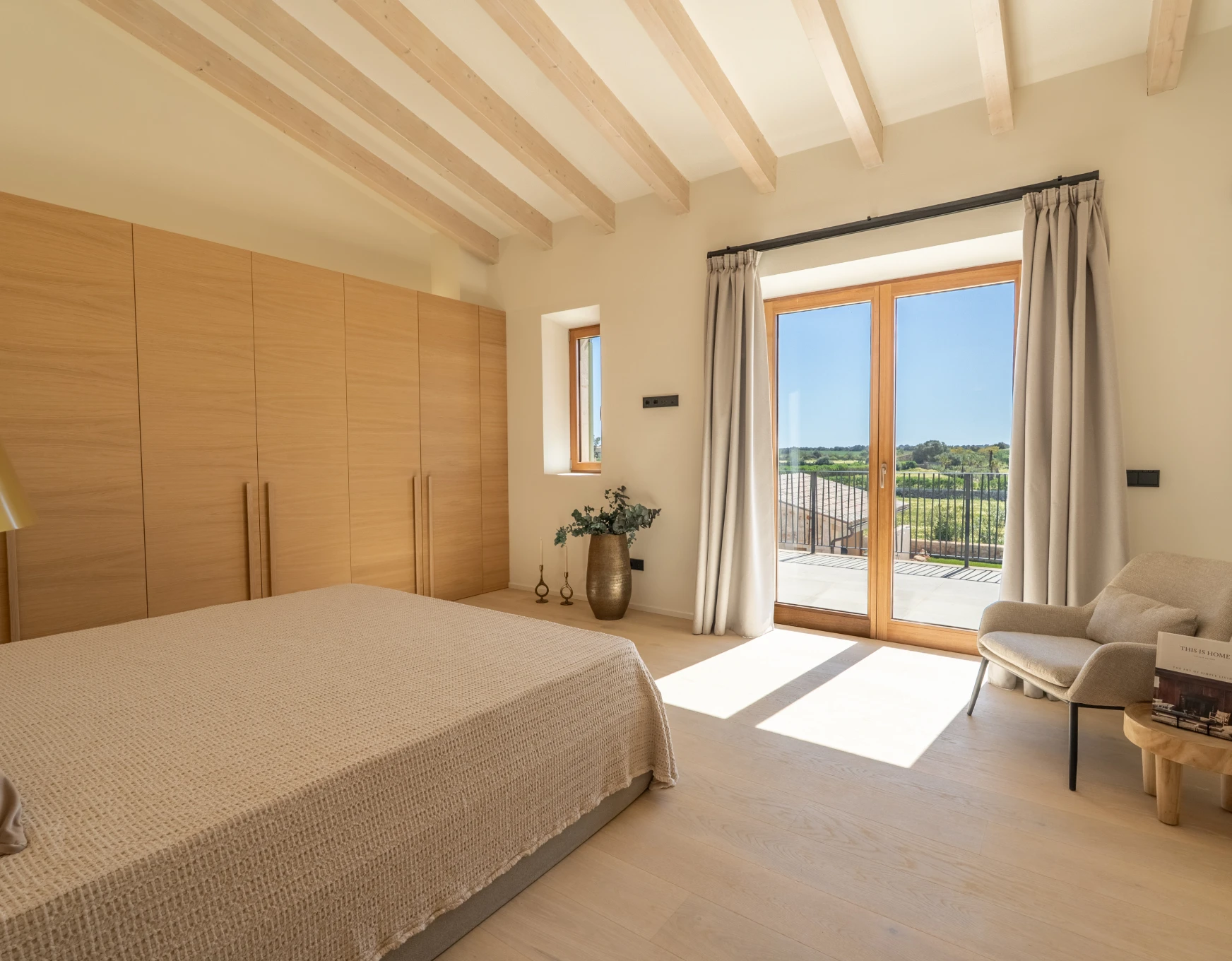 Dormitorio luminoso con vigas y armario de madera recién pintado por pintores en Mallorca